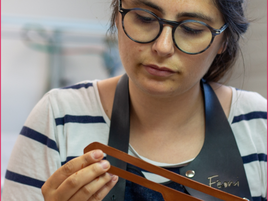 Une femme vérifie une lamelle de cuir sur son poste de travail. 